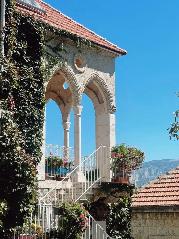 Casa tradizionale libanese con arcate in pietra, rampicanti e fiori