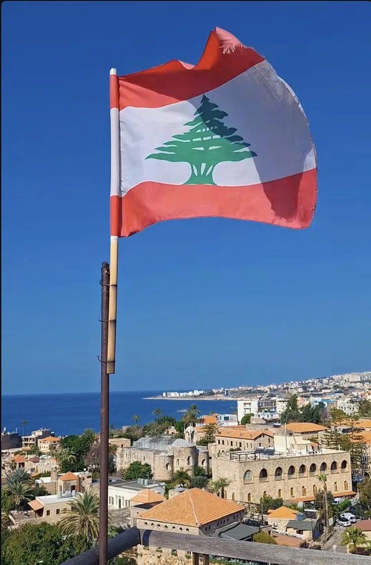 Bandiera del Libano sopra una città costiera in pietra sul Mediterraneo